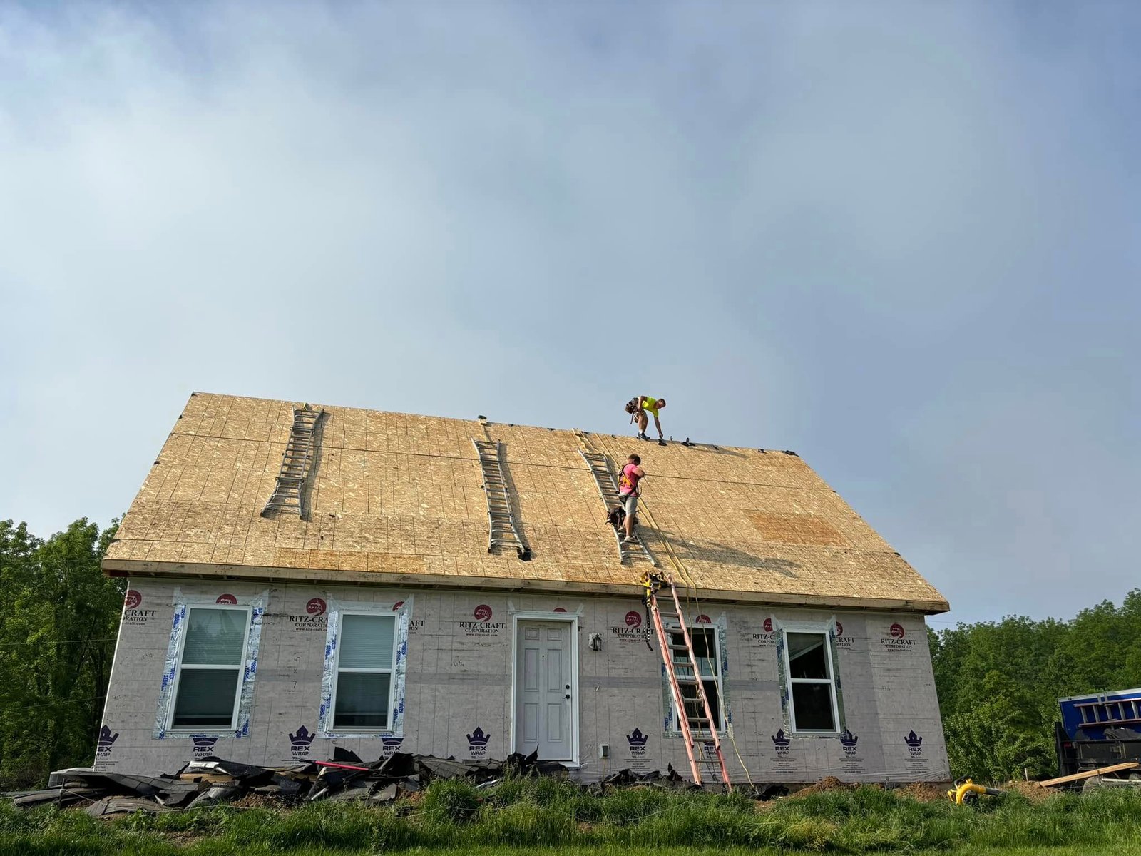 Crew installing new roof and siding roofing work by Hershberger Construction